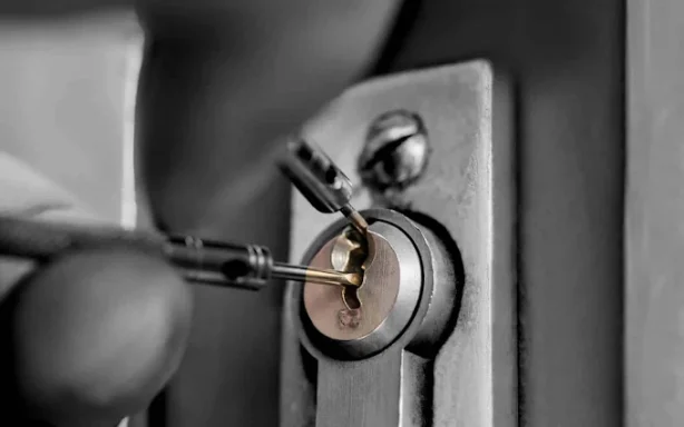 Man picklocking a door lock with tools.