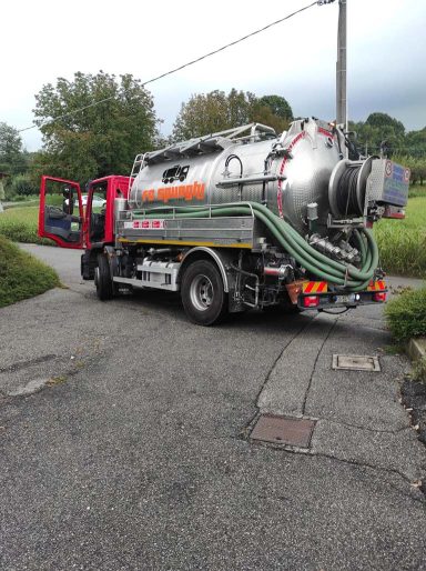 Spurgo H24 Camion aspiratore grigio-argento con tubi verdi, parcheggiato in una strada.